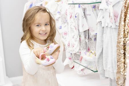 shopping. discounts. little girl shopaholic. girl chooses shoes for her dress. shopping center, shopping. emotionsの写真素材