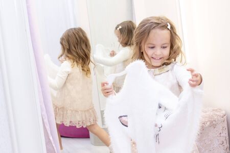shopping. discounts. little shopaholic girl. Girl trying on a beautiful blouse in a fitting room of a boutique. shopping center, shopping. emotionsの写真素材