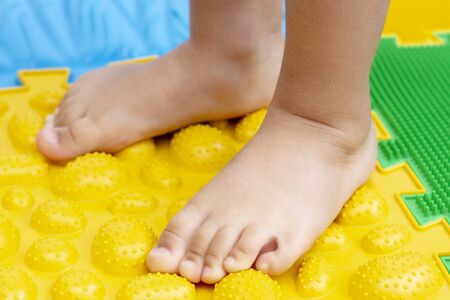 treatment and prevention of flat feet in children. A small child walks barefoot on an orthopedic mat puzzle. Gymnastics for feet are useful for the whole bodyの写真素材