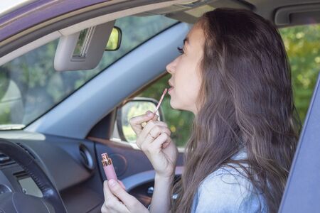 girl driving her car, paints her lips and looks in the car mirror. driver womanの写真素材
