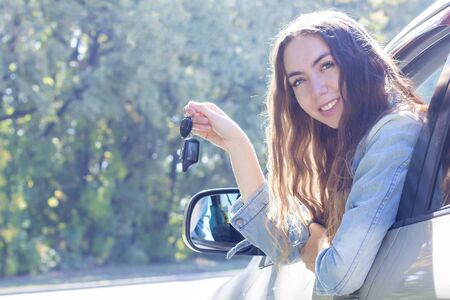 Young woman driving her car. Attractive young girl driver in new car . girl bought a car. shows the keys to a new carの写真素材