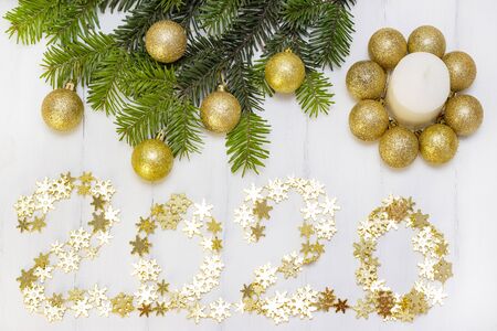 2020 from a gold garland in the form of snowflakes. White candle on the background of the Christmas...