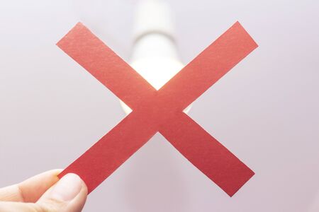 power outage concept. red cross on a background of a burning light bulb. Turn off the light. No...