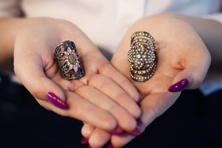 Close up of an elegant ring with stones on woman's hands. concept of wealth, jewelry. The girl holds in her hands two large ringsの写真素材
