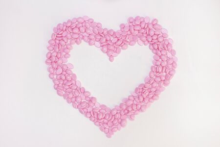 Wax for depilation of pink color. in the form of a heart. On white background. The concept of...
