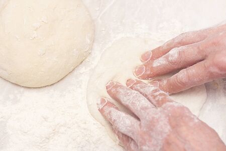 Womens hands, flour and dough. A woman is preparing a dough for home baking. Rolls out the dough...