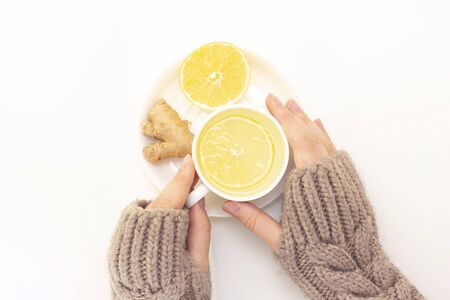 Womans hands with tea, lemon, ginger on a white background.の写真素材