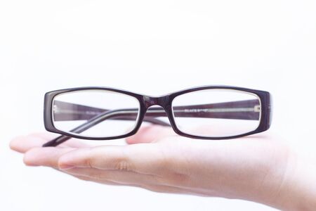 glasses for vision correction in a dark frame. lie in the palm of your hand. on a light background. close-up.の写真素材
