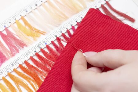 tailor selects the color of the thread in the catalog for the red fabric. atelier shop of fabrics...