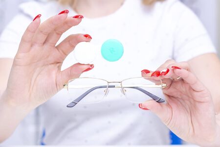 Vision correction. Ophthalmology, excellent vision or optics store concept. The girl makes a choice between glasses and lenses.の写真素材