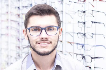 healthcare, people, vision and vision concept. men smiling trying on glasses in the store.の写真素材