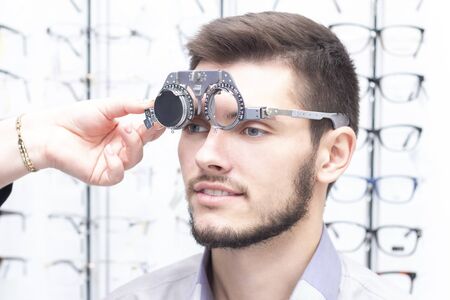 Ophthalmologist examines the young man in the clinic. Consultation of an ophthalmologist. Medical equipment. Correometryの写真素材