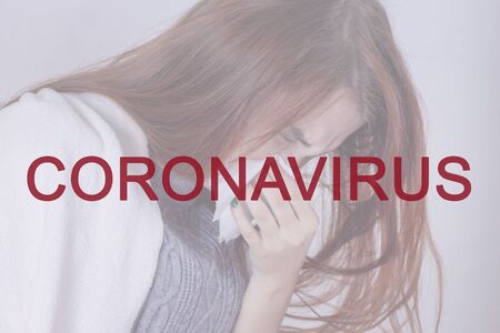 Coronavirus inscription in red. Against the background of a sick girl who sneezes.の写真素材