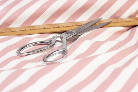 Scissors and a sewing ruler are on cotton striped fabric. natural sewing conceptの写真素材