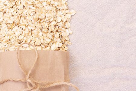 dry natural oat flakes. Oatmeal from an ecological paper bag. Natural linen background with eco bag and oatmeal flakes.の写真素材
