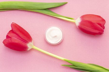 Spring skin care. Tulip and jar of cream on a pink background.