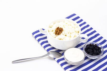 Breakfast concept. cottage cheese with walnuts, raisins and sour cream on a light background and a towel. whiteの写真素材