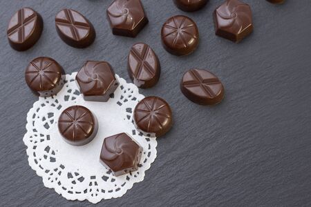 chocolate candies on a black background, cocoa powder. dark photo, mood.