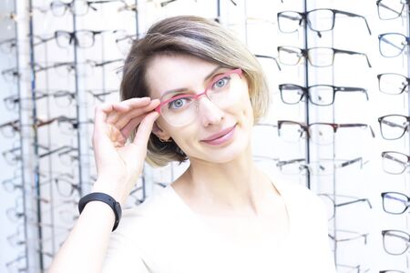 girl in glasses for eyesight. Trying glasses in an optics store. Satisfied girl