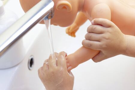child washes his hands a doll. hands in foam of antibacterial soap. Protection against bacteria, coronaviruses. hand hygiene. wash hands with water.の写真素材