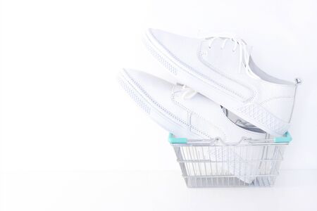 White new sneakers in a shopping basket on a white background. copyspaceの写真素材