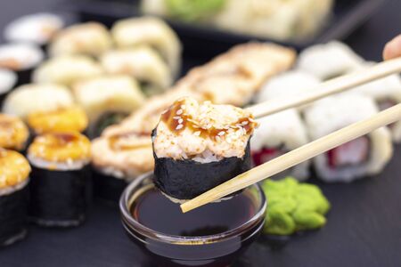 Set of rolls, wasabi, sauce and wooden sticks on a stone black table.の写真素材