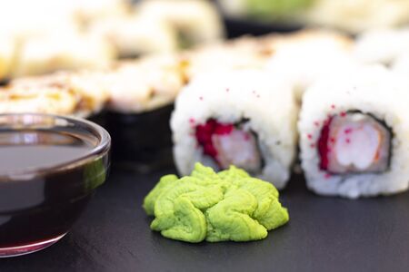 Set of rolls, wasabi, sauce and wooden sticks on a stone black table.の写真素材
