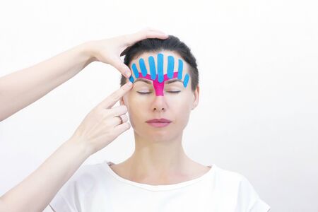 Face taping, close-up of a girls face with cosmetological anti-wrinkle tape. Face aesthetic taping. Non-invasive anti-aging lifting method for reduction of wrinklesの写真素材