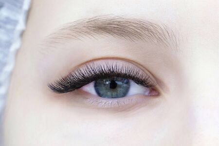 Eyelash extensions. Close-up of eye with extended eyelashes of a white girlの写真素材