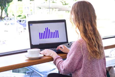 girl works for a laptop. on screen laptop graph, economy and business. remote work, online. girl in...