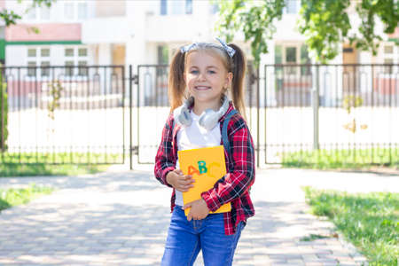 happy schoolgirl with a textbook in her hands. with headphones around the neckの写真素材