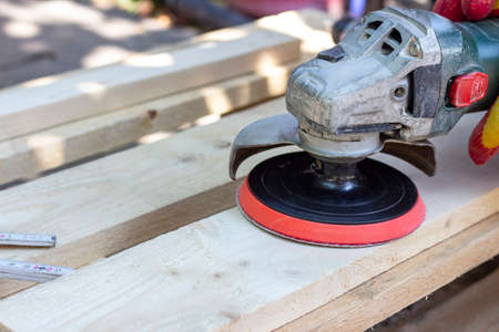 carpenter grinds wood, wood surface treatment with a grinder. woodwork, loft