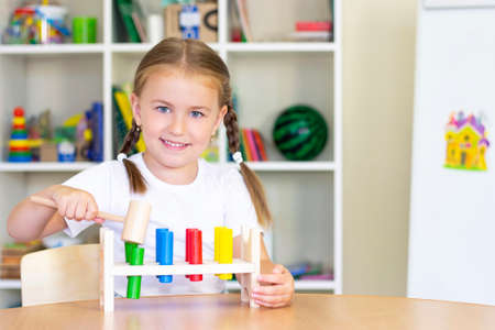 little girl hammers the sticks with a hammer. development of hands and fingers. development of fine motor skillsの写真素材