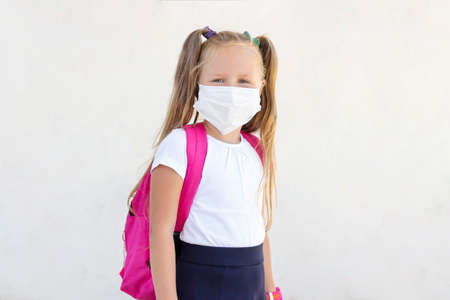 schoolgirl stands with a backpack in a protective medical maskの写真素材
