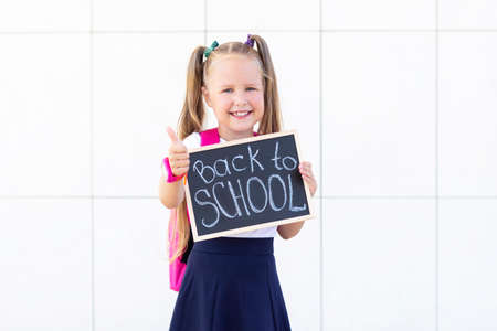 schoolgirl stands with a backpack and a sign with the inscription back to school.の写真素材