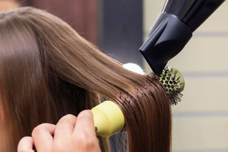 Womens hairdresser, beauty salon. Drying your hair with a hair dryer and a round brush.の写真素材