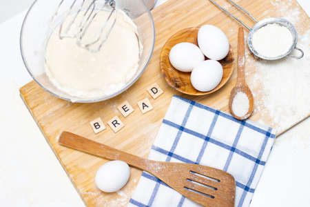 making dough for bread or homemade baked goods. ingredients on a wooden table. inscription: breadの写真素材