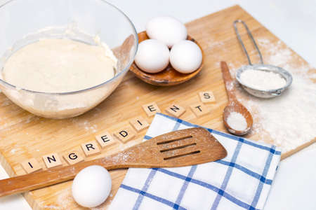 making dough for bread or homemade baked goods. ingredients on a wooden table. inscription: ingredientsの写真素材
