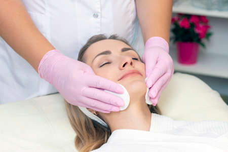 cosmetology. Close up picture of lovely young woman with closed eyes receiving facial cleansing...