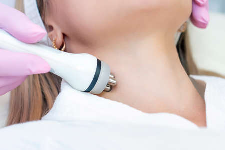 Hardware cosmetology. Close up picture of lovely young woman with closed eyes receiving rf lifting procedure in beauty salon.の写真素材