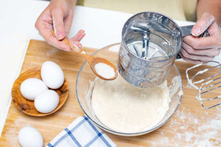 Home cooking concept. Female hands prepare homemade dough on a floured wooden board. Close-up.