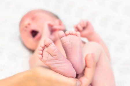 parent holds the legs of a newborn child.