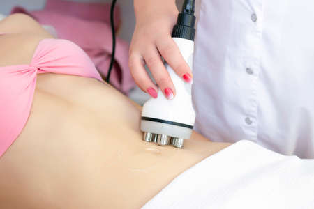 procedure removing cellulite on female abdomen, cavitation belly massage. Ultrasonic massage for weight loss. Correction of female figure without surgical intervention. Closeup of the tummy.の写真素材