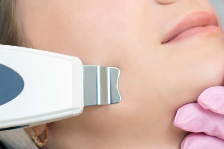 Cosmetologist makes an ultrasonic cleaning of the face of a young woman. close upの写真素材