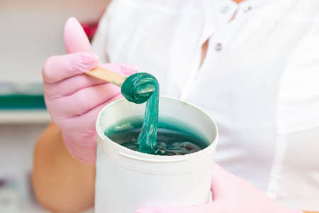 Liquid sugar for skin epilation. Close shot. cosmetologist holding a jar of sugar paste for depilation.の写真素材