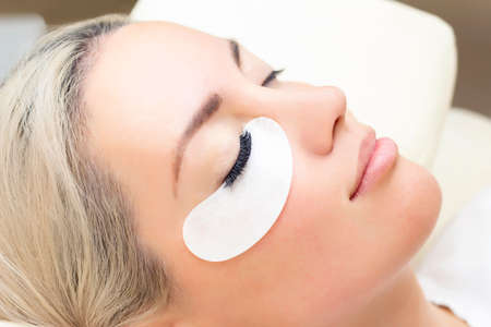 Eyelash extension procedure. Woman eye with long eyelashes. Close up