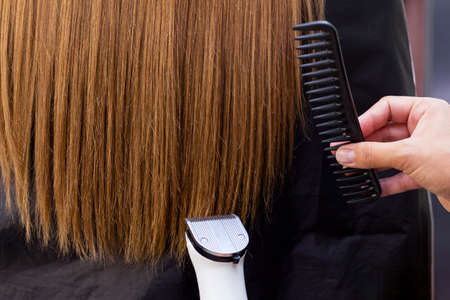 Hairdresser with a hair machine. cutting off split ends of hair with a clipper. close up. trimming split endsの写真素材