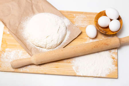 Home cooking concept. Female hands prepare homemade dough on a floured wooden board.
