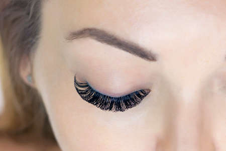 Eyelash extension procedure. Woman eye with long eyelashes. Close upの写真素材