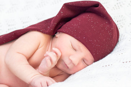 newborn baby sleeps in a gnome hat and smiles. close up portrait of beautiful sleeping babyの写真素材
